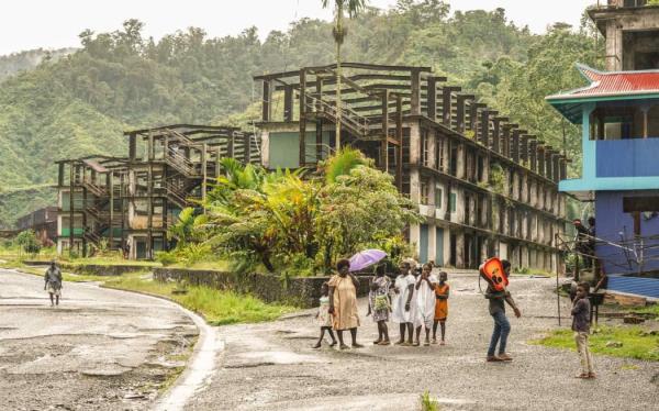 Locals walk by buildings left abando<em></em>ned by a subsidiary of Rio Tinto at the Panguna mine site.