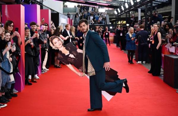 LONDON, ENGLAND - OCTOBER 17: Andrew Garfield poses with a cardboard cutout of Florence Pugh at the 