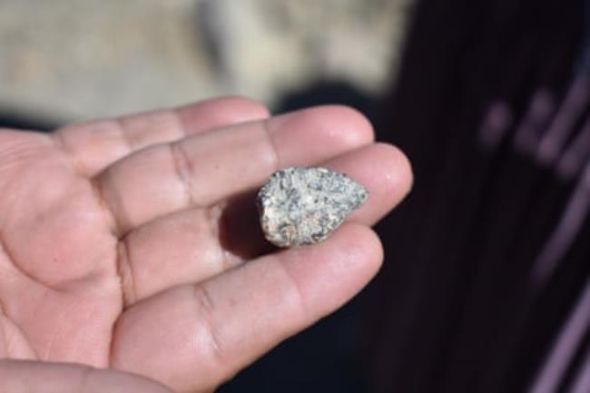 A hand holds a small piece of rock