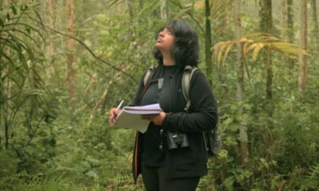 Ishika Ramakrishna stands in the forest with a pen and notepad