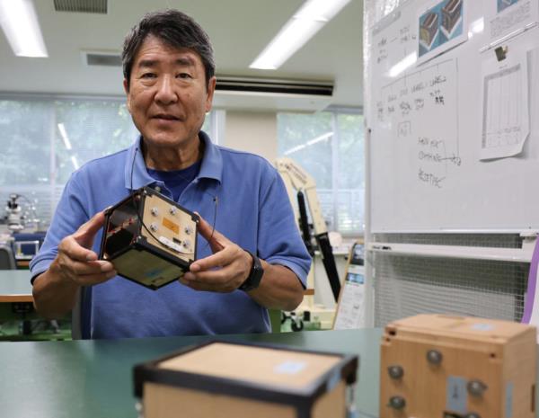 Takao Doi holds an engineering model of LignoSat during an interview with Reuters at his laboratory at Kyoto University in Kyoto