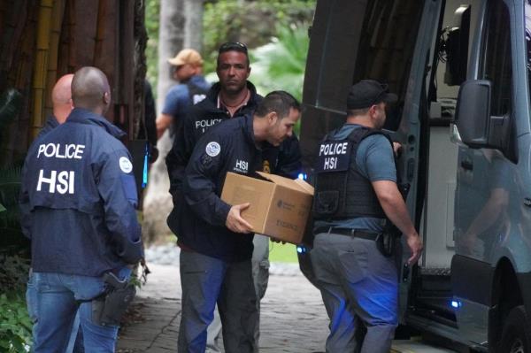Law enforcement officers removing boxes from Diddy's Miami mansion during a raid on March 25, 2024.