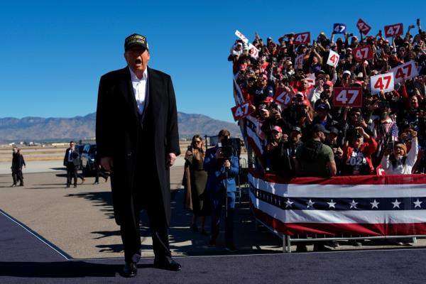 Former President Do<em></em>nald Trump, wearing a black suit and hat, at a 2024 Campaign rally in Albuquerque, with a crowd of people watching.