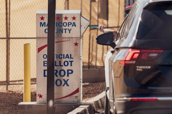 An Arizona voter dropping their ballot into a ballot drop box at the Maricopa County Tabulation and Election Center