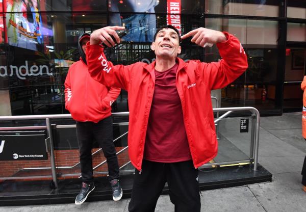 A Top View worker in a red jacket pointing his fingers up, harassing a New York Post photographer, with Chad Wolf behind.