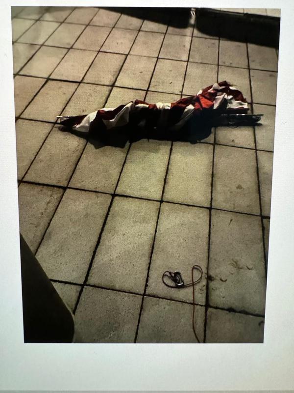 The flag was left crumpled on the sidewalk.
