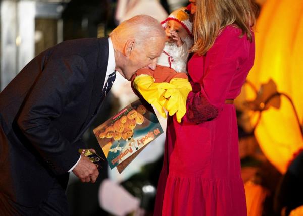 Biden playfully bites a baby's thigh during a Halloween event on Oct. 30 at the White House.