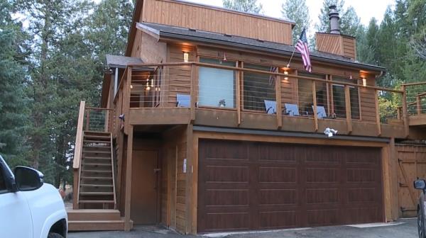 The wood paneled outside of the two story Airbnb can be seen situated in a wooded area.