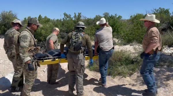 Terrell County Sheriff Thaddeus Cleveland assists fellow law enforcement officers in carrying a body on a stretcher along the border