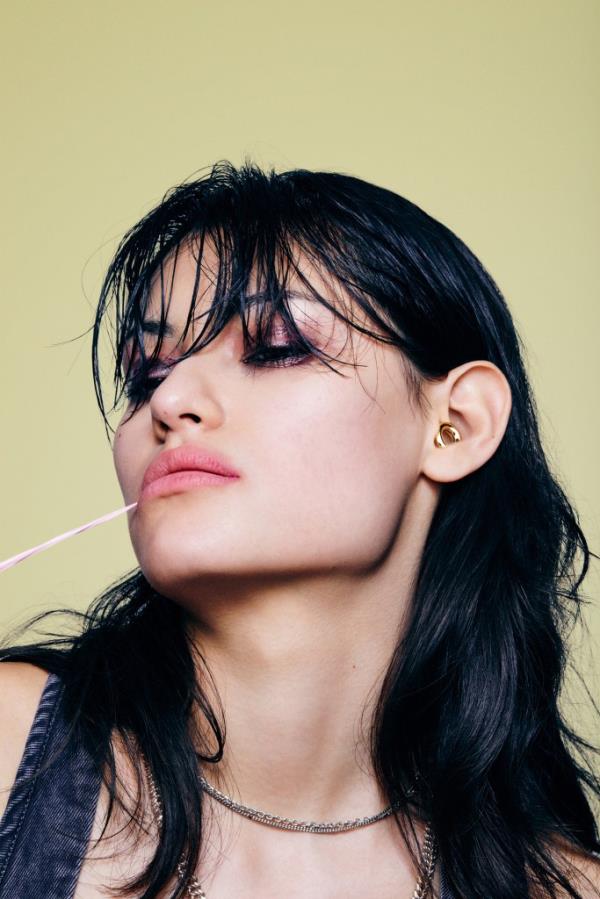 Woman with long black hair and pink lipstick wearing Loop Quiet 2 Earplugs