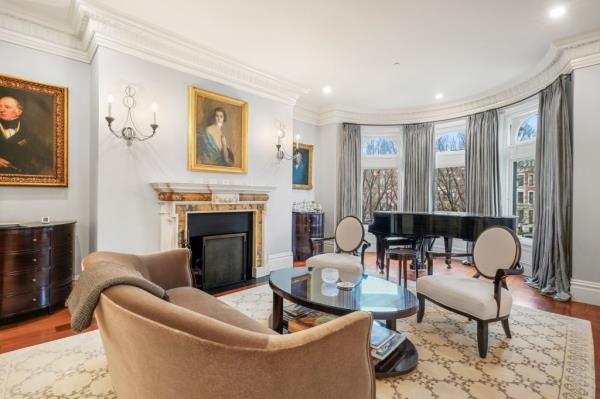 A large living room has circular bay windows and a fireplace with an elegant mantel.