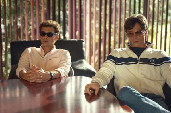 Cooper Koch as Erik Menendez and Nicholas Chavez as Lyle Menendez sitting at a table in a scene from Monsters: The Lyle And Erik Menendez Story on Netflix