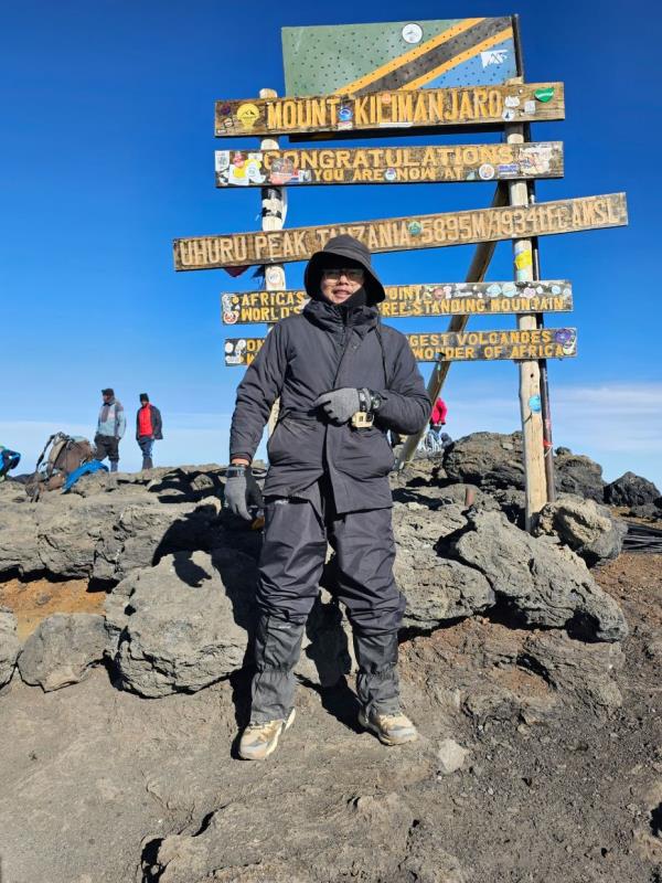 The writer in front of the Uhuru Peak sign.