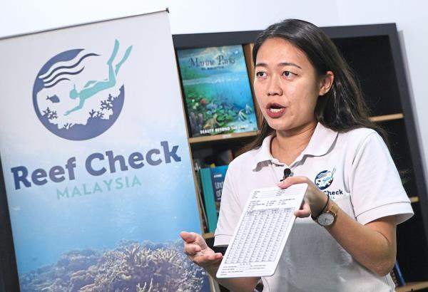Ng holding a dive slate used by divers for reef surveys.