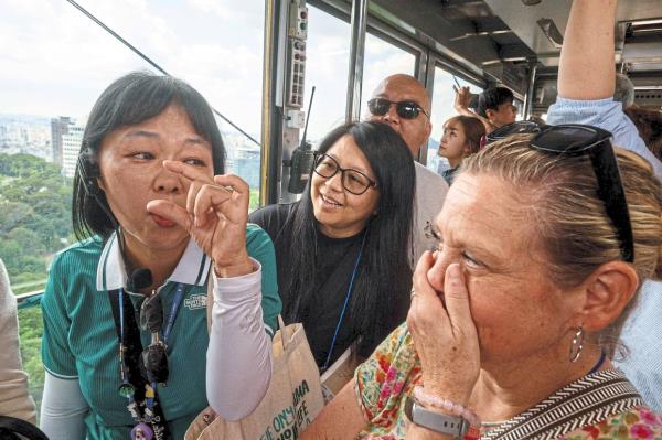 Sophy (left) gestures as she speaks to American tourist Jeanie Barry (right) while riding the cable car up to Namsan Tower in Seoul, during a K-drama tour. — Photos: AFP
