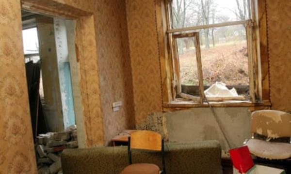 damaged room with broken window showing wintry scene outside, rubble and dust