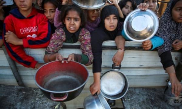 Palestinians gather to receive food cooked by a charity kitchen in Khan Younis, southern Gaza, 19 November 2024.