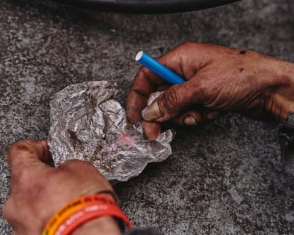 Two hands hold a tinfoil wrapper open to reveal fentanyl 