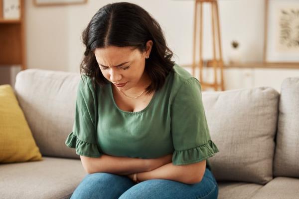 Stress, stomach pain and woman on a sofa with constipation