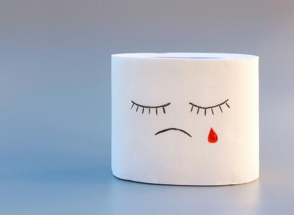 Toilet paper with sad face, co<em></em>ncept of hemorrhoid treatment