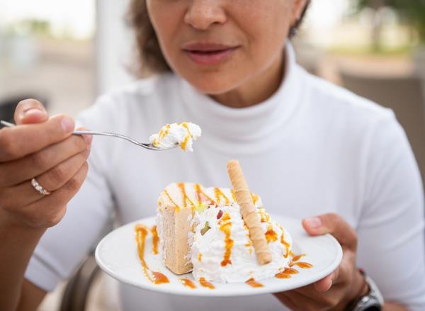 A woman eating a piece of cake covered in whipped cream 