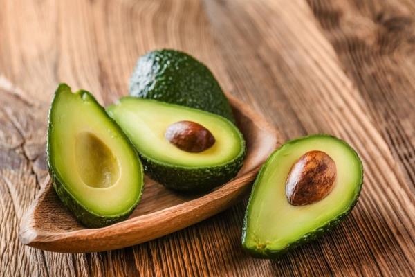 Half and whole avocados on a wood surface