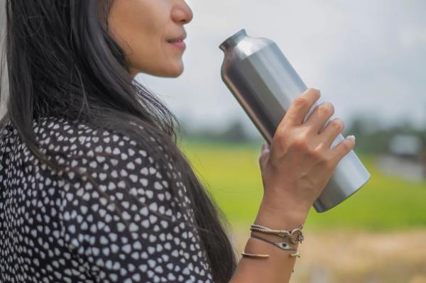 Close-up shot of a woman drinking water from a reusable stainless steel bottle