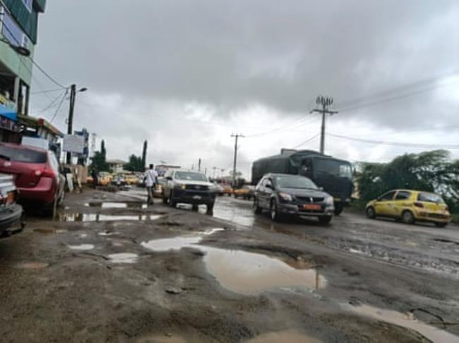 A road with large, water-filled potholes.