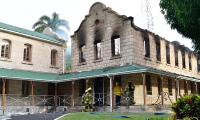 A burned-out building, with fire crew in front of it