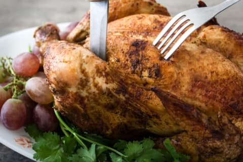 A knife and fork in a turkey that's a<em></em>bout to be carved.