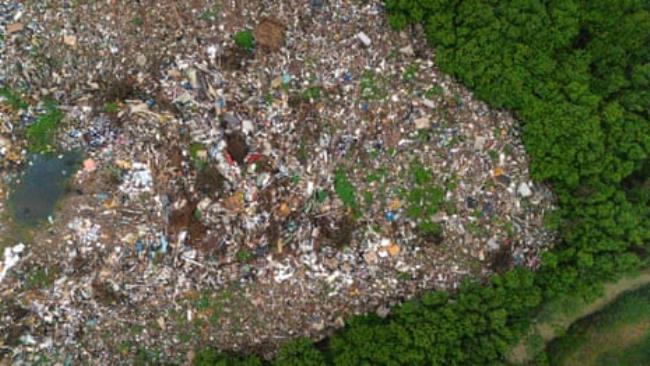 Aerial view of a huge mound of debris beside forest