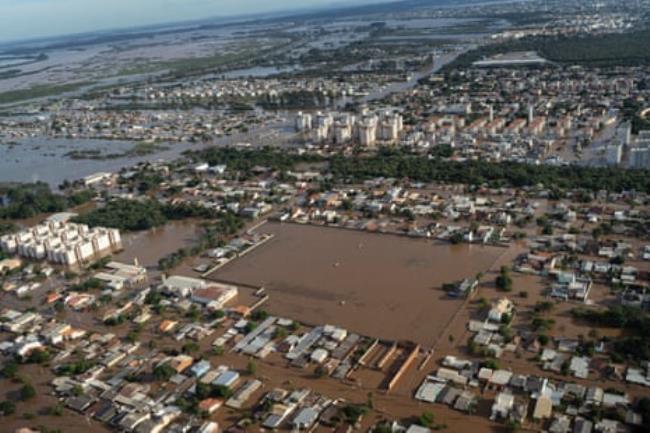Aerial view of flood water surrounding largely single-storey houses. 