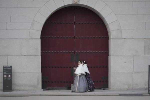 Tourists wearing traditio<em></em>nal hanbok walking in front of the Gwanghwamun, the main gate of the 14th-century Gyeo<em></em>ngbok Palace in Seoul on Dec 4. -- AP