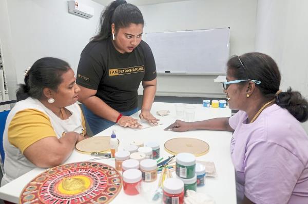Guiding hands: Art instructor Marriyaee Anthony (centre) demo<em></em>nstrates the art of lippan kaam to Magespari (left) and Vinothini.