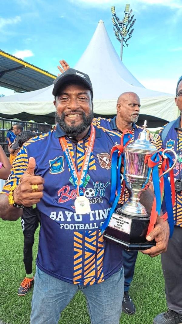 In good hands: Grassroots football coach K. Sivakumar with the Malaysian Indian Football Association (Mifa) Under-12 category winner’s trophy.