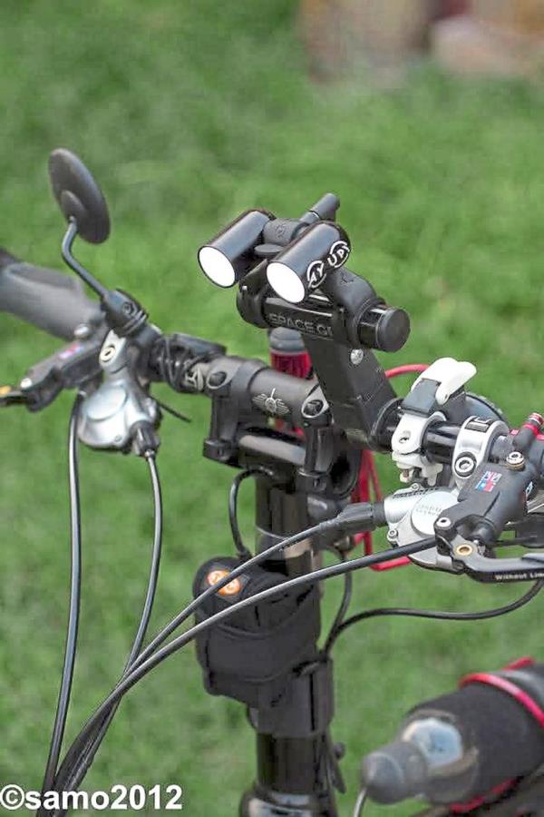 Twin lights mounted on a bike handlebar. High-powered lights not o<em></em>nly illuminate your path but also signal your presence from afar, creating a safer riding environment.