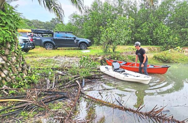 Readying a kayak and red canoe by a lake shore.