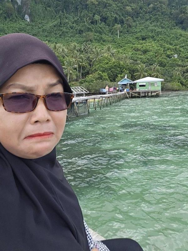 Sitti on her boat looking at her family home.