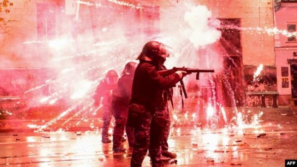 FILE - Fireworks shot by protesters explode near police in riot gear firing tear gas during a natio<em></em>nwide protests against the Georgian government's decision to shelve EU membership talks, in Tbilisi, Dec. 2, 2024.