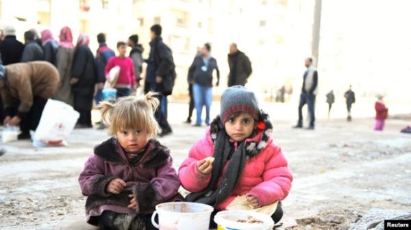 FILE - Girls eat a cooked meal provided by the U.N. through a partner NGO in the east Aleppo neighborhood of al-Bab, Syria, in this handout picture provided by UNHCR, Jan. 4, 2017.