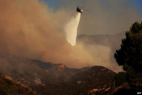 A helicopter drops water as the Franklin Fire grows in Malibu, California, on Dec. 10, 2024.