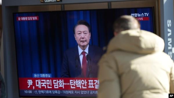 A man watches a TV screen showing the live broadcast of South Korean President Yoon Suk Yeol's announcement at the Seoul Railway Station in Seoul, South Korea, Dec. 7, 2024.