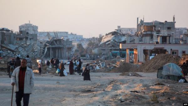 Palestinians walk in a devastated neighborhood due to Israeli strikes in the southern Gaza Strip city of Khan Yunis on Dec. 2, 2024,