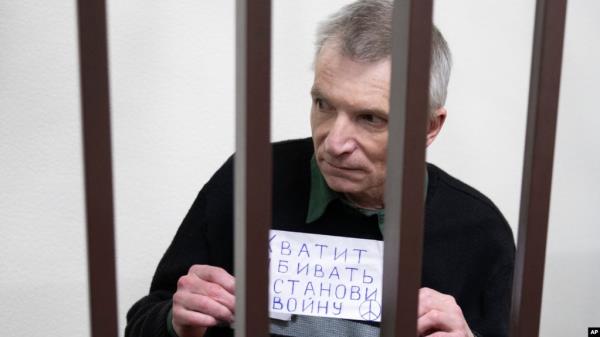 Impriso<em></em>ned Kremlin critic Alexei Gorinov stands in a cage at the court holding a banner saying 