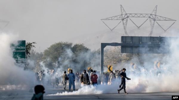 Members of jailed former prime minister Imran Khan's Pakistan Tehreek-e-Insaf (PTI) party attempt to throw back teargas shells fired by riot police as they protest during a march to Islamabad demanding Khan's release in Hasan Abdal in Punjab province on November 25, 2024.