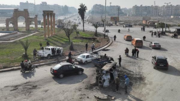 People stand near a damaged vehicle, after rebels led by HTS have sought to capitalize on their swift takeover of Aleppo in the north and Hama in west-central Syria by pressing o<em></em>nwards to Homs, in Hama, Syria December 6, 2024. Photo: REUTERS/Mahmoud Hasano