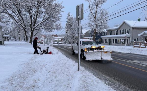 A person clears the snow from the sidewalk in Lowville, New York.