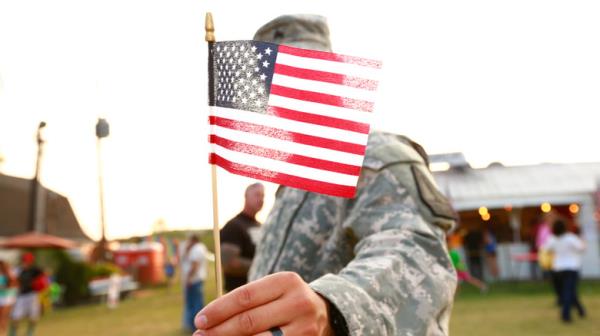 Soldier holding up flag to camera