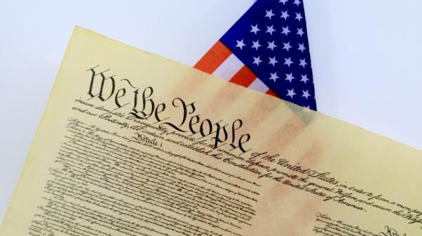 The United States Co<em></em>nstitution in front of an American flag