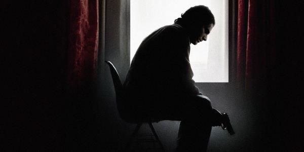 Avner (Eric Bana) sitting on a chair holding a gun in Munich